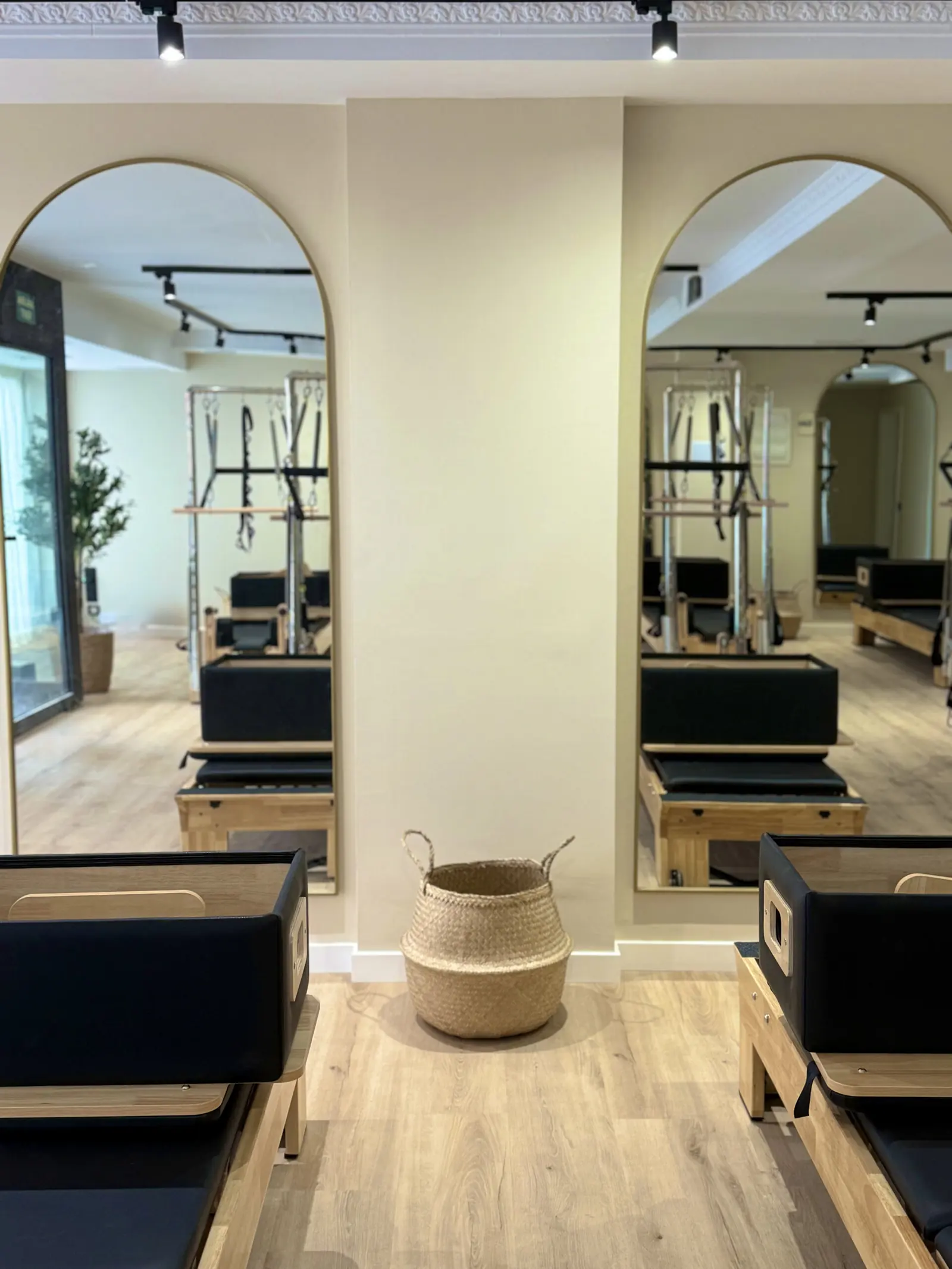La sala de ACTIUM: suelo de madera, paredes crema y espejos en arco